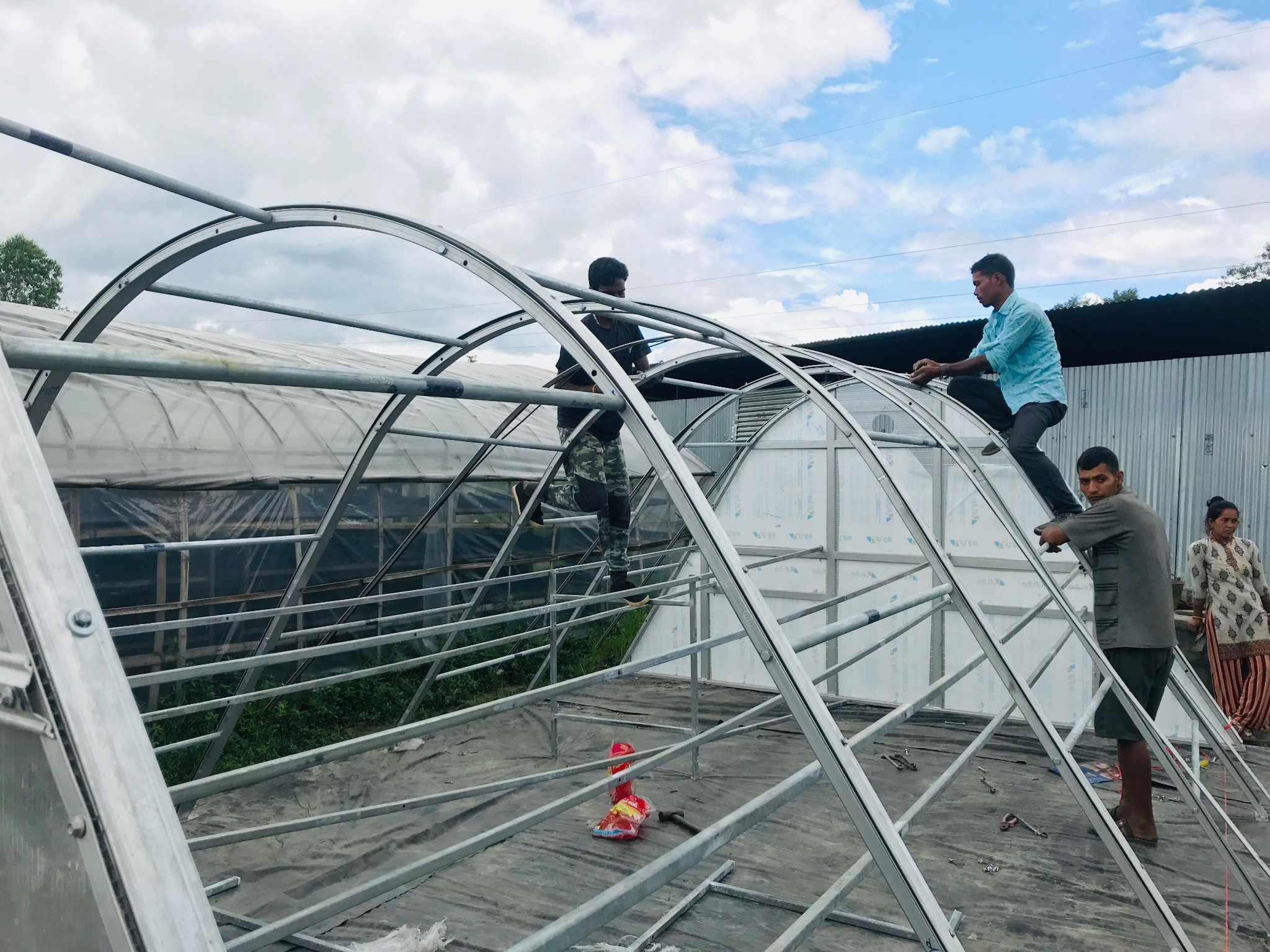 Workers installing the curved greenhouse dryer frame at Sanga
